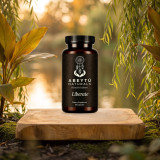 Liberate bottle on a wooden slab by a river at golden hour, among willow and turmeric leaves