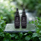 Two InsuLess dropper bottles on wet slate among fresh mint beside a woodland brook